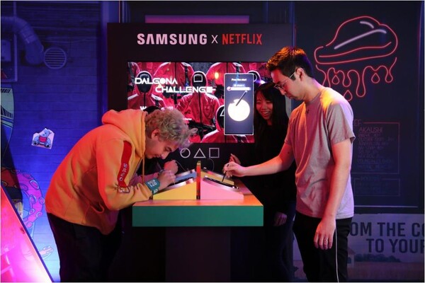 삼성전자는 넷플릭스가 미국 로스앤젤레스에 개장한 체험존인 ‘오징어게임: 더 트라이얼’의 공식 파트너사로 참여했다. 참가자들이 갤럭시 S23 울트라의 S펜으로 디지털 달고나 게임을 즐기고 있다. [제공=삼성전자]