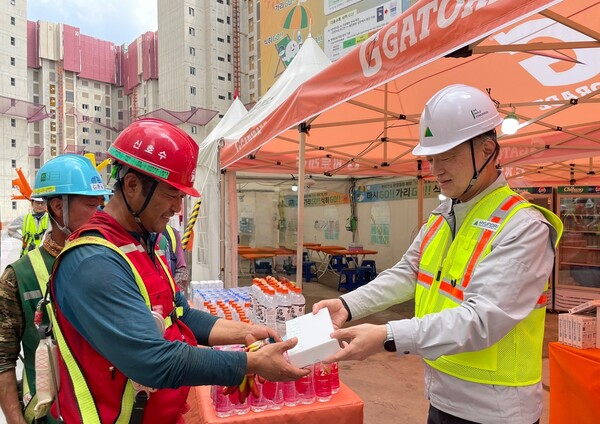 현대건설 CSO 황준하 전무가 근로자에게 수분 보충과 탈수 예방을 위한 이온음료와 쿨링스프레이를 직접 전달하고, 근로자들의 노고를 격려하고 있다.