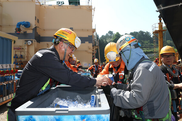 한화오션 김희철 대표이사(왼쪽)가 거제사업장 1도크 주변에서 근로자들에게 시원한 음료를 건네주고 있다.